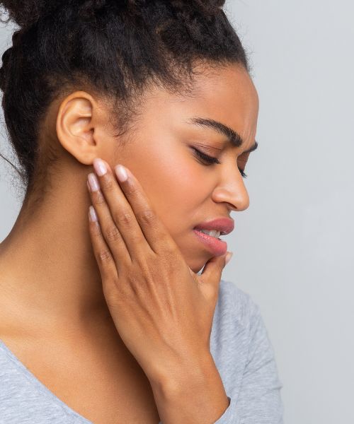 Woman portraying jaw pain from a dental implant bridge