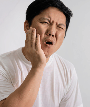 Man holding the right side of his face due to pain from a possible root tip left behind after an extraction